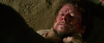Movie still from “Lone Survivor” (2013), directed by Peter Berg – A person laying on the ground covered in blood; Close Up shot, Over the shoulder angle