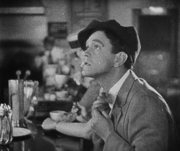 Movie still from “Lonesome” (1928), directed by Pál Fejös – A man sitting at a table with a cat in front of him; Close Up shot, Low angle