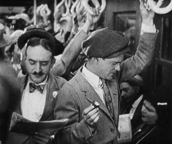 Movie still from “Lonesome” (1928), directed by Pál Fejös – A black and white photo of a group of men in suits and hats; Medium shot, High angle