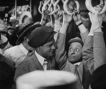 Movie still from “Lonesome” (1928), directed by Pál Fejös – A black and white photo of a group of men holding hands; Medium shot, Low angle