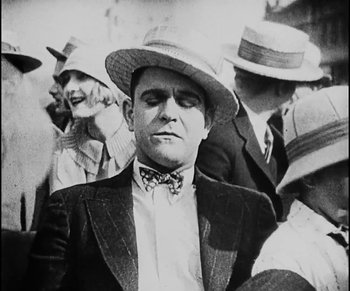 Movie still from “Lonesome” (1928), directed by Pál Fejös – An old photo of a man in a suit and a hat; Close Up shot, High angle