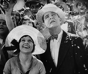 Movie still from “Lonesome” (1928), directed by Pál Fejös – A man and a woman wearing hats in a crowd of onlookers; Medium shot, Low angle