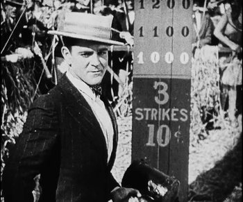 Movie still from “Lonesome” (1928), directed by Pál Fejös – A man wearing a hat standing next to a wooden pole; Medium shot, Over the shoulder angle
