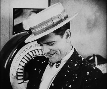 Movie still from “Lonesome” (1928), directed by Pál Fejös – A black and white photo of a man wearing a hat; Medium shot, Low angle