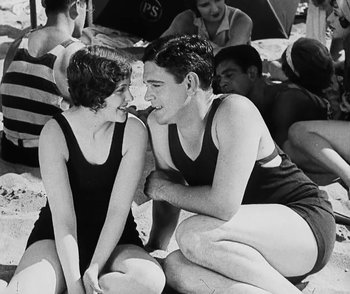 Movie still from “Lonesome” (1928), directed by Pál Fejös – A man and a woman sitting next to each other on the beach; Medium shot, High angle
