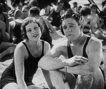 Movie still from “Lonesome” (1928), directed by Pál Fejös – A man and a woman sitting on the beach; Medium shot, High angle