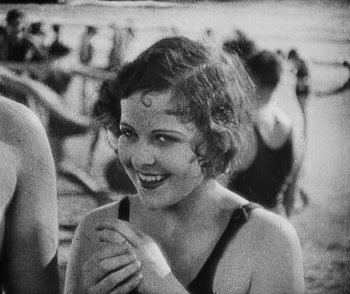 Movie still from “Lonesome” (1928), directed by Pál Fejös – An old black and white photo of a woman smiling; Close Up shot, High angle