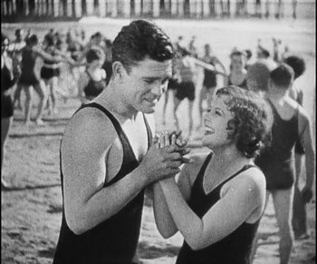 Movie still from “Lonesome” (1928), directed by Pál Fejös – A man and a woman in bathing suits on the beach; Medium shot, Low angle
