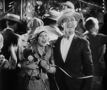 Movie still from “Lonesome” (1928), directed by Pál Fejös – A man and a woman are standing in front of a crowd of onlookers; Medium shot, High angle