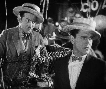 Movie still from “Lonesome” (1928), directed by Pál Fejös – Two men in hats and ties are sitting next to each other; Medium shot, Low angle