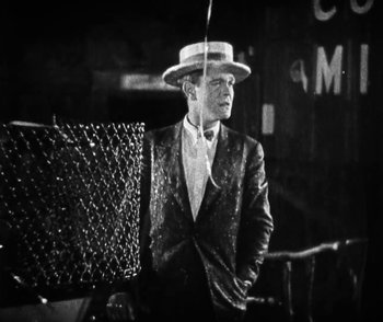 Movie still from “Lonesome” (1928), directed by Pál Fejös – A black and white photo of a man in a suit and hat; Medium shot, High angle