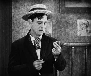 Movie still from “Lonesome” (1928), directed by Pál Fejös – A man wearing a suit and a straw hat is looking at his cell phone; Medium shot, High angle