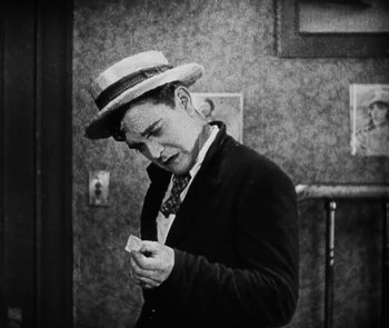 Movie still from “Lonesome” (1928), directed by Pál Fejös – A black and white photo of a man wearing a hat; Medium shot, High angle