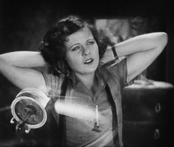 Movie still from “Lonesome” (1928), directed by Pál Fejös – An old black and white photo of a woman holding her hands behind her head; Medium shot, Low angle