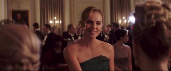 Movie still from “Long Shot” (2019), directed by Jonathan Levine – A woman in a green dress smiling for the camera; Medium shot, Over the shoulder angle