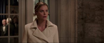 Movie still from “Long Shot” (2019), directed by Jonathan Levine – Charlize theron in a white coat looking to her left; Medium shot, Over the shoulder angle