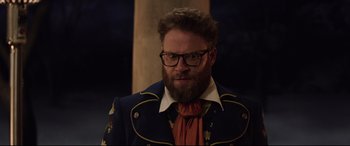 Movie still from “Long Shot” (2019), directed by Jonathan Levine – A man with a beard wearing a suit and tie; Medium shot, Over the shoulder angle