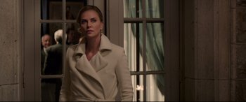 Movie still from “Long Shot” (2019), directed by Jonathan Levine – A woman in a white coat standing in front of a window; Medium shot, Over the shoulder angle