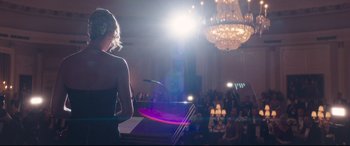 Movie still from “Long Shot” (2019), directed by Jonathan Levine – A woman standing in front of a microphone in front of a crowd; Medium shot, Over the shoulder angle