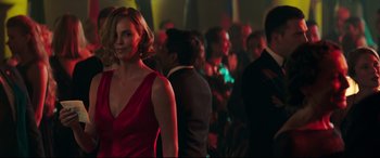 Movie still from “Long Shot” (2019), directed by Jonathan Levine – A woman in a red dress standing next to a group of people; Medium shot, Over the shoulder angle