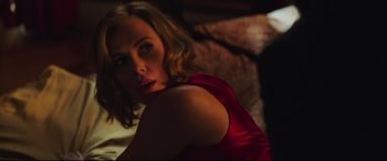Movie still from “Long Shot” (2019), directed by Jonathan Levine – A woman in a red dress sitting on a couch; Medium shot, Over the shoulder angle