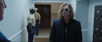 Movie still from “Long Shot” (2019), directed by Jonathan Levine – A woman in a suit and sunglasses standing in front of two men; Medium shot, Over the shoulder angle
