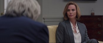 Movie still from “Long Shot” (2019), directed by Jonathan Levine – A woman sitting on a couch in front of another person; Medium shot, Over the shoulder angle