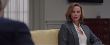 Movie still from “Long Shot” (2019), directed by Jonathan Levine – A woman sitting on top of a couch in a room; Medium shot, Over the shoulder angle