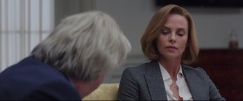 Movie still from “Long Shot” (2019), directed by Jonathan Levine – A woman sitting in front of a man in a suit; Close Up shot, Over the shoulder angle