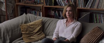 Movie still from “Long Shot” (2019), directed by Jonathan Levine – A woman sitting on top of a couch in a living room; Medium shot, Over the shoulder angle