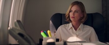 Movie still from “Long Shot” (2019), directed by Jonathan Levine – Charlize theron sitting at a desk in a white shirt; Close Up shot, Over the shoulder angle