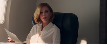 Movie still from “Long Shot” (2019), directed by Jonathan Levine – A woman in a white shirt sitting on a black chair; Close Up shot, Over the shoulder angle