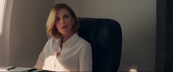 Movie still from “Long Shot” (2019), directed by Jonathan Levine – A woman in a white shirt sitting on a black chair; Close Up shot, Over the shoulder angle