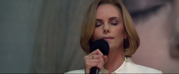 Movie still from “Long Shot” (2019), directed by Jonathan Levine – A beautiful woman holding a microphone up to her face; Close Up shot, Low angle