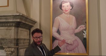 Movie still from “Long Shot” (2019), directed by Jonathan Levine – A man standing in front of a painting of a woman; Medium shot, Over the shoulder angle