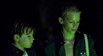 Movie still from “Lord of the Flies” (1990), directed by Harry Hook – Two young boys are standing next to each other in the dark; Medium shot, Low angle