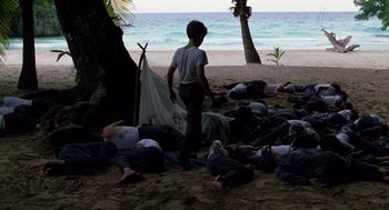 Movie still from “Lord of the Flies” (1990), directed by Harry Hook – A group of people laying on the beach; Wide shot, High angle