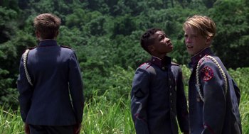 Movie still from “Lord of the Flies” (1990), directed by Harry Hook – A group of people standing next to each other on top of a grass covered hillside; Medium shot, Low angle