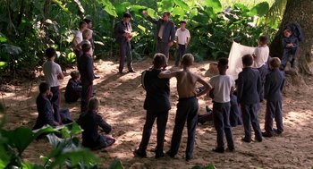 Movie still from “Lord of the Flies” (1990), directed by Harry Hook – A group of people standing in the dirt; Wide shot, High angle