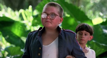 Movie still from “Lord of the Flies” (1990), directed by Harry Hook – A young boy with glasses and a jacket on; Close Up shot, Low angle