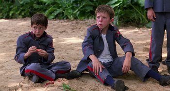Movie still from “Lord of the Flies” (1990), directed by Harry Hook – Two boys sitting on the ground in the sand; Medium shot, High angle