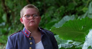 Movie still from “Lord of the Flies” (1990), directed by Harry Hook – A person wearing glasses standing in front of a tree; Close Up shot, Low angle