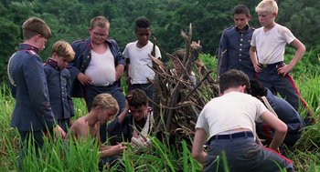 Movie still from “Lord of the Flies” (1990), directed by Harry Hook – A group of young men standing in a grassy field; Wide shot, High angle