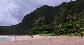 Movie still from “Lord of the Flies” (1990), directed by Harry Hook – Two people walking on a beach near a mountain; Extreme Wide shot, High angle