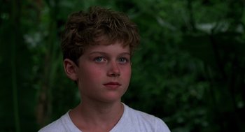 Movie still from “Lord of the Flies” (1990), directed by Harry Hook – A young boy with blue eyes stares into the distance; Close Up shot, Over the shoulder angle
