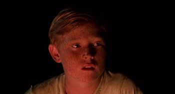 Movie still from “Lord of the Flies” (1990), directed by Harry Hook – A young boy with red hair is looking at the camera; Close Up shot, High angle