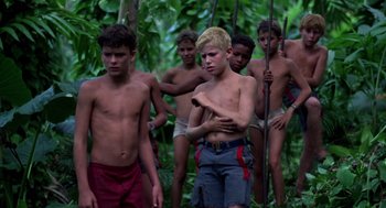 Movie still from “Lord of the Flies” (1990), directed by Harry Hook – A group of young men standing next to each other in the woods; Medium shot, Low angle
