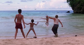 Movie still from “Lord of the Flies” (1990), directed by Harry Hook – A group of people on the beach playing in the water; Wide shot, Low angle