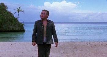 Movie still from “Lord of the Flies” (1990), directed by Harry Hook – A young man walking on the beach near the water; Wide shot, Low angle