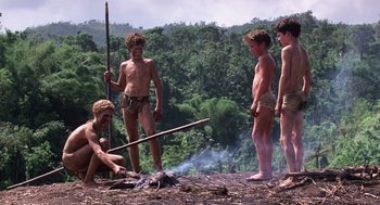 Movie still from “Lord of the Flies” (1990), directed by Harry Hook – A group of young men standing around a fire; Wide shot, Low angle